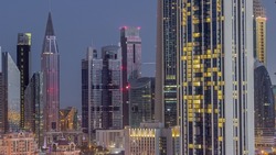 Row of the tall buildings around Sheikh Zayed Road and DIFC district aerial night to day transition timelapse in Dubai, UAE. International Financial Centre skyscrapers with glass surface before