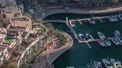 Dubai Marina waterfront with promenade aerial timelapse, Dubai, UAE. Many restaurants and floating yachts and boats. People sitting on a bench