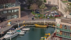 Waterfront promenade with palms in Dubai Marina aerial timelapse. Yachts and boats floating on water near reataurant