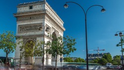 The Arc de Triomphe (Triumphal Arch of the Star) timelapse is one of the most famous monuments in Paris, standing at the western end of the Champs-Elyseees. Traffic on circle road. Blue cloudy sky at