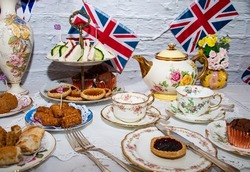 Queen Elizabeth II Platinum Jubilee cream tea street party food red white and blue flags  with celebration Union jack food toppers on a white vintage table cloth with Union jack flags