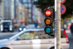 blurred view of city traffic with traffic lights, in the foreground a traffic light with a red light