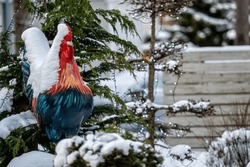a snowy figure of a rooster and fir trees at the entrance of the cafe, close-up