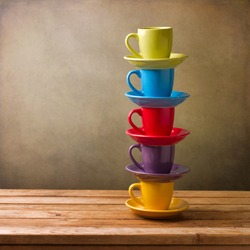 Colorful coffee cups on wooden table over grunge background