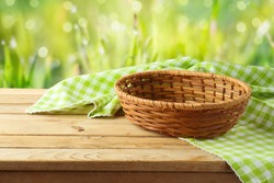 Empty basket with tablecloth on wooden table over green bokeh background. Spring and easter mock up for design.