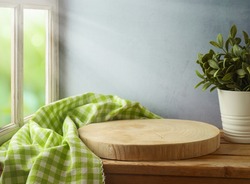 Empty wooden log board with tablecloth on wooden table over window and wall background. Spring and Easter mock up for design.