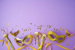 Flat lay composition for carnival or mardi gras background with golden carnival masks on violet background. Top view