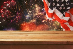 4th of July background. Wooden table over fireworks and USA flag. Independence day celebration