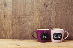 Coffee cups on wooden table with chalkboard sign and best friends text. Friendship day celebration background