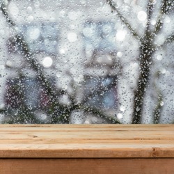 Empty wooden deck table over wet glass window. Rainy weather concept. Background for product montage display