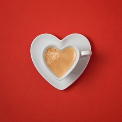 Heart shape coffee cup over red background. View from above