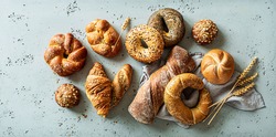 Bakery - various kinds of breadstuff. Bread rolls, bagel, sweet bun and croissant captured from above (top view, flat lay). Grey stone background.