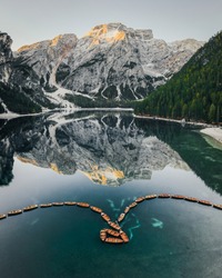 Beautiful view of the mountain lago di Braies in the Dolomites. Mirror reflection of a mountain in a lake. Morning mountain summer landscape of boats on the water.