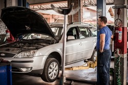 Car mechanic working in a repair garage with hydraulic car lift. Automobile elevator