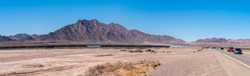 Panoramic View of Highway With Large Solar Farm on the Side of the Road and Large Mountains Formation on the background