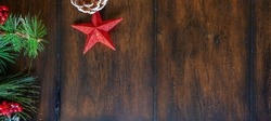 View of Sparkly Red Star On Dark Wood Table With Pine Needles and Berries on the Left Side