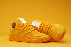 Yellow tennis modern shoes isolated on orange background