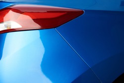 Blue car backlight  close-up. Shiny new polished blue car paint