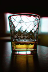 Half empty glass of whiskey drink with chromatic aberrations