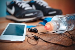 Bottle with water,  smartphone, earphones and sneakers at a background. Set for sports activities