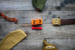 Flask, cap , george ribbon, soldier belt with a five-pointed star with a hammer and sickle and a wooden calendar with the date February 23. Fatherland defender day. Text in Russian