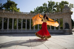 Young beautiful indian woman wearing traditional indian clothes, dancing bollywood dance outdoors