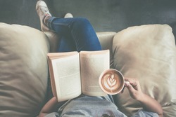 Soft photo of young girl reading a book and drinking coffee, top view