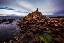 Man standing on top of basalt columns at Giant's Causeway, Ireland