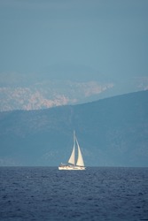 Beautiful seascape with white sailing ship in blue see on mountains background
