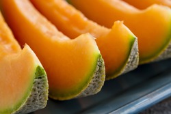 Cantaloupe melon slices sitting on blue platter in a row