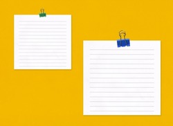 Blank note paper with clip on yellow art paper background and have copy space for your design.