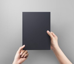 Hands women holding black book cover blank top view.  Blank book cover.
