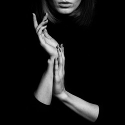 Femme fatale concept. Old classic movies actress style. Close up portrait of gorgeous young woman with beautiful hands over black background. Black and white studio shot