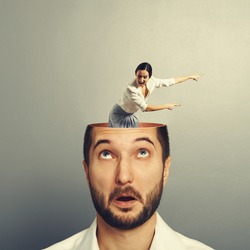 amazed businessman with open head. young screaming businesswoman standing into the head, looking at the man and showing the direction. photo over grey background