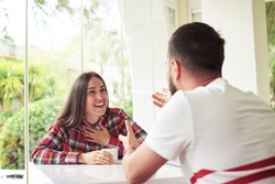 Young man and woman are sitting in bright sunlit room with garden view and vigorously discussing something