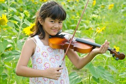 Little girl with violin in the sunflower field