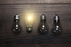 glowing bulb uniqueness concept on brown wooden background
