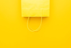 shopping paper bag on the yellow background with copy space. flat lay photo of upturned yellow bag. summer sale concept