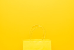 shopping paper bag on the yellow background with copy space. flat lay photo of yellow bag. summer sale concept