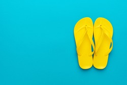 pair of yellow beach flip-flops on the blue background summer concept. minimalist flat lay photo of beach flip-flops with some copy space