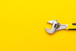 adjustable wrench with yellow handle on the yellow background