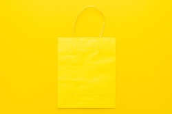 Shopping paper bag on the yellow background with copy space. Flat lay mockup photo of yellow bag.