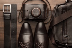 brown shoes, belt, bag and film camera on the wooden table