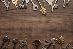 many different keys on brown wooden background with copy space in the centre