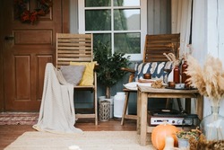 porch of the backyard decorated with pumpkins and dry grass in autumn, rustic furniture on veranda of a rustic house, a cozy and stylish interior in autumn colors