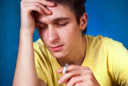 Sad Young Man with a Cigarette on the Blue Background closeup