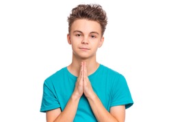 Portrait of teen boy praying, isolated on white background. Cute caucasian teenager with hands folded in prayer hoping for better. Child asking God for good luck, success or forgiveness.