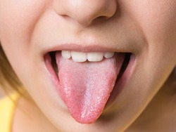 Nice girl showing her tongue. Child puts out tongue - close up.