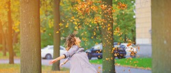 Cute young hipster millennial girl in purple blue autumn dress throwing dry fall leaves up in air with hands. Happy woman atmospheric autumn relax Freedom mind peace wind fresh breath concept banner.