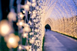 Christmas decoration in the park path. Colourful decor lights lantern tunnel in the evening  in the city during winter.